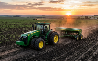 Trator John Deere 6110J 4x4 verde no campo ao pôr do sol
